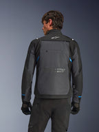 Alpinestars Cusco Drystar® Jacke, Motorradjacke, Schwarz und Dunkelgrau, Rückansicht an einem Model mit großem grauen Rückenteil, weißem Alpinestars-Logo und blauen Akzenten an den Ärmeln.