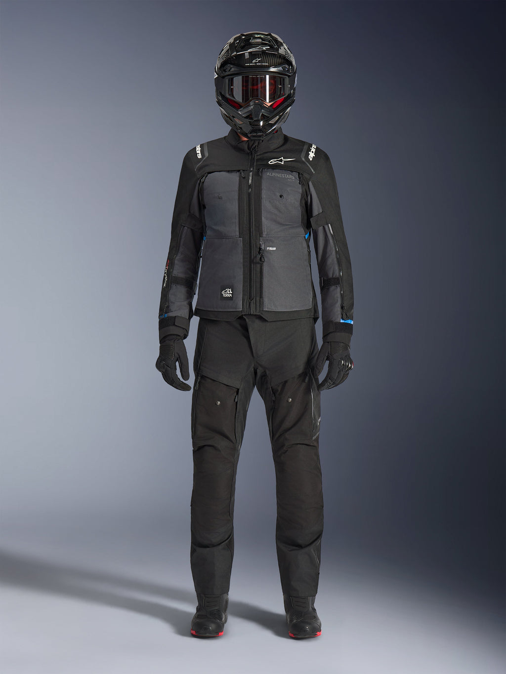Alpinestars Cusco Drystar® Jacke, Adventure-Touring-Jacke in Schwarz und Dunkelgrau, getragen mit passender schwarzer Hose, Handschuhen und einem Integralhelm, Ganzkörperansicht von vorne, Motorrad-Schutzkleidung