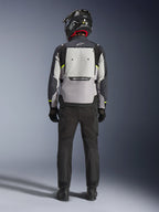 Motorradfahrer in der Rückansicht mit der Alpinestars Cusco Drystar® Jacke in Ice Gray, Mid Gray und Deep Gray, mit großem Belüftungspanel am Rücken und Alpinestars-Branding, kombiniert mit einer schwarzen Motorradhose und einem schwarzen Helm, Adventure-Touring-Motorradbekleidung.