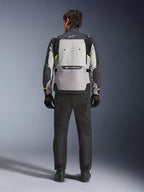 Rückansicht eines Fahrers, der die Alpinestars Cusco Drystar® Jacke in Ice Gray, Mid Gray und Deep Gray trägt, kombiniert mit einer schwarzen Motorradhose und Handschuhen, wobei das große Belüftungspanel am Rücken und das Alpinestars-Branding hervorgehoben werden.