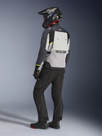Alpinestars Cusco Drystar® Jacke in Ice Gray, Mid Gray und Deep Gray, Rückansicht an einem Fahrer. Ausgestattet mit neongelben Akzenten, einem großen Belüftungspanel am Rücken mit Branding und einer strapazierfähigen Textilkonstruktion. Getragen mit einer schwarzen Motorradhose und einem Adventure-Helm für einen kompletten Touring-Look.