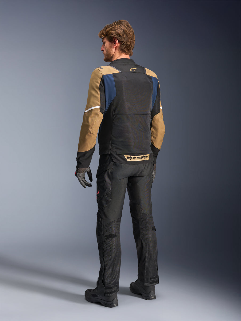 Alpinestars ST-2 Air Jacke, Sommer-Touren-Motorradjacke, Tiefblau, Dunkelkhaki und Schwarz, Rückansicht am Modell mit Mesh-Einsätzen, khakifarbenen Ärmeln und blauen Akzenten, weiße Reflexstreifen und markantes Branding am unteren Rücken, kombiniert mit einer schwarzen Motorradhose