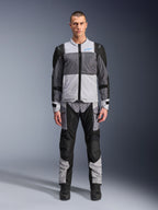 Alpinestars ST-2 Air Jacke, Motorrad-Tourenjacke, Eisgrau, Dunkelgrau und Schwarz, getragen von einem Modell mit passender Adventure-Hose, mit großen Mesh-Einsätzen, blauem Alpinestars-Logo auf der Brust und Alpinestars Exploration Equipment-Branding.
