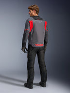 Männlicher Fahrer von hinten in der Alpinestars St-2 Air Jacke in Deep Gray, Dark Gray und Bright Red, präsentiert das große Mesh-Belüftungspanel am Rücken und das rote Branding, kombiniert mit einer schwarzen Motorradhose und grauen Handschuhen.