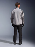 Alpinestars Maxdura Drystar®XF Laminierte Gepanzerte Jacke, Motorradjacke in Mittelgrau und Dunkelgrau, Rückansicht, mit hellgrauem Hauptteil und dunkelgrauen Einsätzen an Schultern und Ärmeln, kleinem roten Alpinestars-Sternlogo am hinteren Kragen und weißem Branding am unteren linken Ärmel, kombiniert mit schwarzer Motorradhose und Stiefeln.