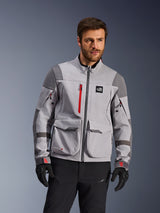 Alpinestars Maxdura Drystar®XF Laminierte Gepanzerte Schale, Adventure-Motorradjacke, Mittelgrau und Dunkelgrau mit roten Akzenten, getragen von einem Model mit schwarzen Handschuhen und Hosen, mit großen Cargotaschen und wasserdichten Reißverschlüssen, professionelle Fahrerausrüstung