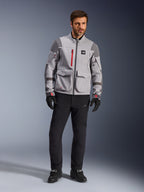 Alpinestars Maxdura Drystar®XF Laminierte Gepanzerte Jacke, Adventure-Motorradjacke, Mittelgrau und Dunkelgrau mit roten Akzenten, getragen mit schwarzer Motorradhose und Handschuhen, Frontansicht mit Fokus auf technische Konstruktion und große Cargotaschen.