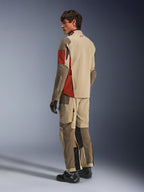 Männliches Model in der Alpinestars Maxdura Drystar®XF laminierten gepanzerten Schale in Aluminum Walnut Rust Brown, dazu passende Adventure-Tourenhose, schwarze Handschuhe und schwarze Stiefel; Rückansicht, die die technische Textilkonstruktion und die verstärkten Zonen zeigt.