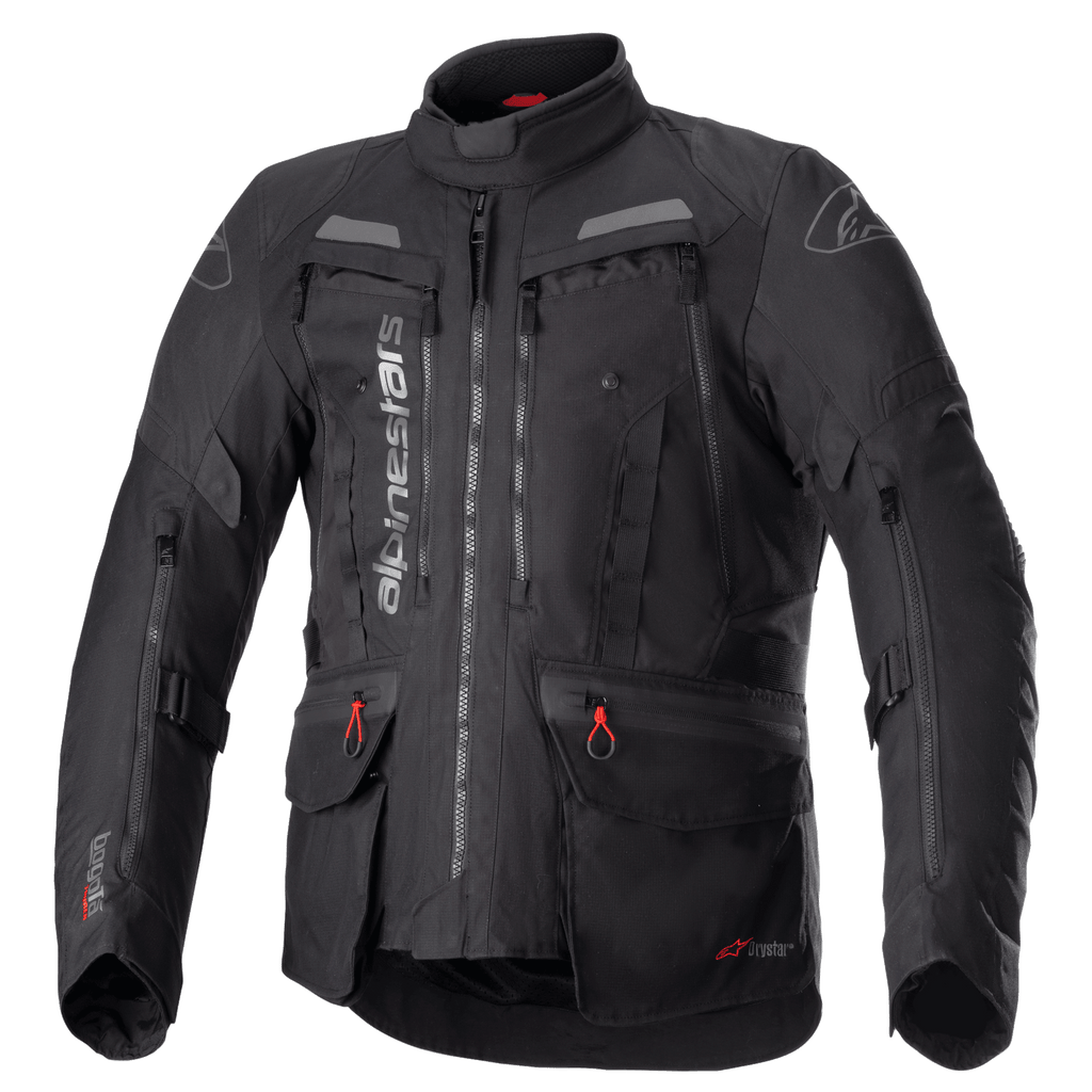 Alpinestars Bogota Pro Drystar Jacke, komplett schwarze Motorrad-Tourenjacke, graue und rote Akzente, große Belüftungspaneele an der Brust, wasserdichte Taschen mit roten Zuglaschen, hoher Schutzkragen, strapazierfähige Textilkonstruktion für Adventure-Fahrten