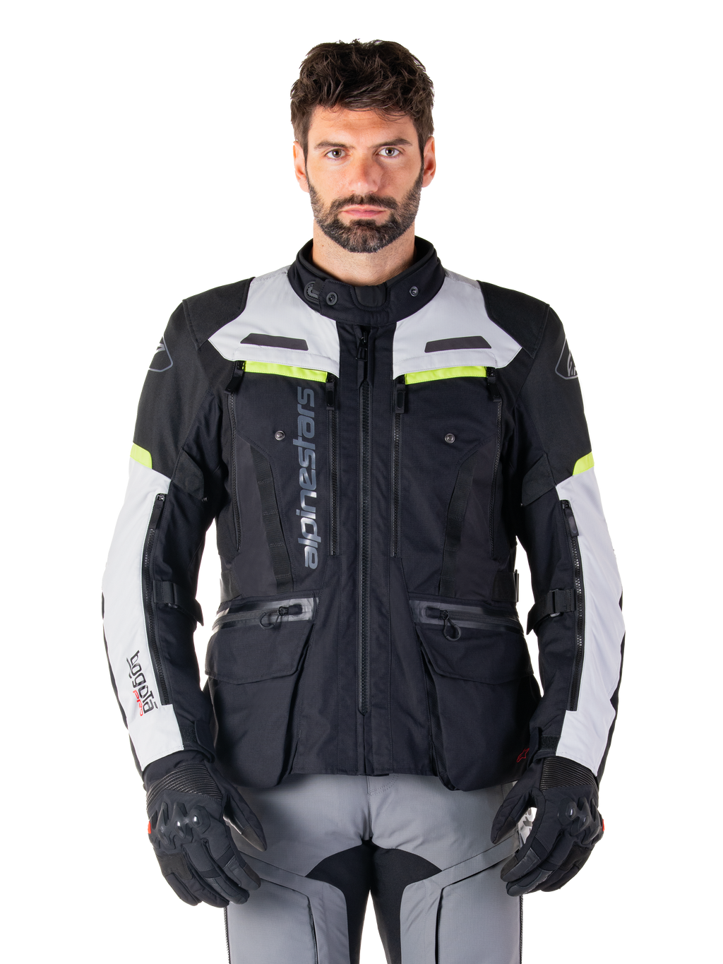 Mann in Alpinestars Bogotá Pro Drystar® Jacke, Schwarz, Ice Gray und Yellow Fluo, Ganzjahres-Adventure-Touring-Motorradjacke, wasserdichtes Design mit mehreren Taschen und vertikalem Branding, kombiniert mit schwarzen Handschuhen und grauer Motorradhose