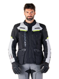 Mann in Alpinestars Bogotá Pro Drystar® Jacke, Schwarz, Ice Gray und Yellow Fluo, Ganzjahres-Adventure-Touring-Motorradjacke, wasserdichtes Design mit mehreren Taschen und vertikalem Branding, kombiniert mit schwarzen Handschuhen und grauer Motorradhose