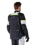 Alpinestars Bogotá Pro Drystar® Jacke, Adventure-Tourenjacke, Schwarz, Ice Gray und Gelb Fluo, Rückansicht mit großem Rückentaschen-Panel und „TECH TOURING“-Branding, Alpinestars-Logo und fluoreszierenden Akzenten, technische Textil-Fahrausrüstung