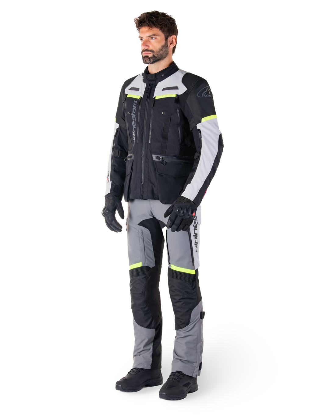 Alpinestars Bogotá Pro Drystar® Jacke, Adventure-Touring-Motorradjacke, Black Ice Gray Yellow Fluo, getragen von einem Model mit passender Hose und schwarzen Handschuhen, wasserdichte Textilkonstruktion mit Belüftungspanelen und fluoreszierenden Akzenten.