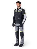 Alpinestars Bogotá Pro Drystar® Jacke, Adventure-Touring-Motorradjacke, Black Ice Gray Yellow Fluo, getragen von einem Model mit passender Hose und schwarzen Handschuhen, wasserdichte Textilkonstruktion mit Belüftungspanelen und fluoreszierenden Akzenten.
