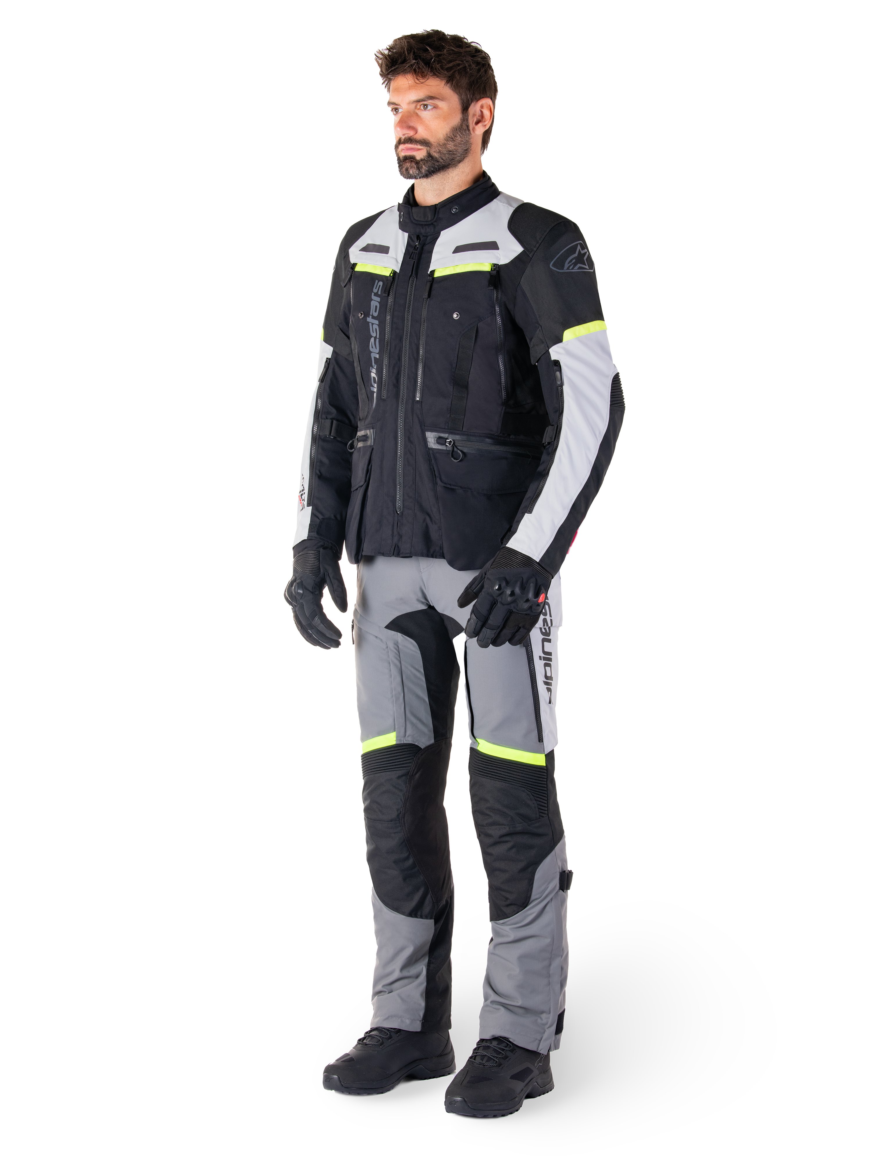 Alpinestars Bogotá Pro Drystar® Jacke, Adventure-Touring-Motorradjacke, Black Ice Gray Yellow Fluo, getragen von einem Model mit passender Hose und schwarzen Handschuhen, wasserdichte Textilkonstruktion mit Belüftungspanelen und fluoreszierenden Akzenten.