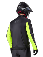 Alpinestars Bogotá Pro Drystar® Jacke, Rückansicht, Schwarz mit Gelb Fluo Ärmeln, getragen von einem Fahrer mit schwarzem Helm und Handschuhen, hochsichtbare Adventure-Touring-Motorradausrüstung mit technischem Textil-Finish.