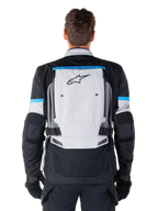 Alpinestars Bogota' Pro Drystar® Jacke, Adventure-Motorradjacke, Eisgrau, Schwarz und Cyan, Rückansicht mit einem großen hellgrauen Panel mit schwarzem Stern-Logo, cyanfarbenen Akzenten mit Tech-Touring-Branding und verstellbaren Taillengurten