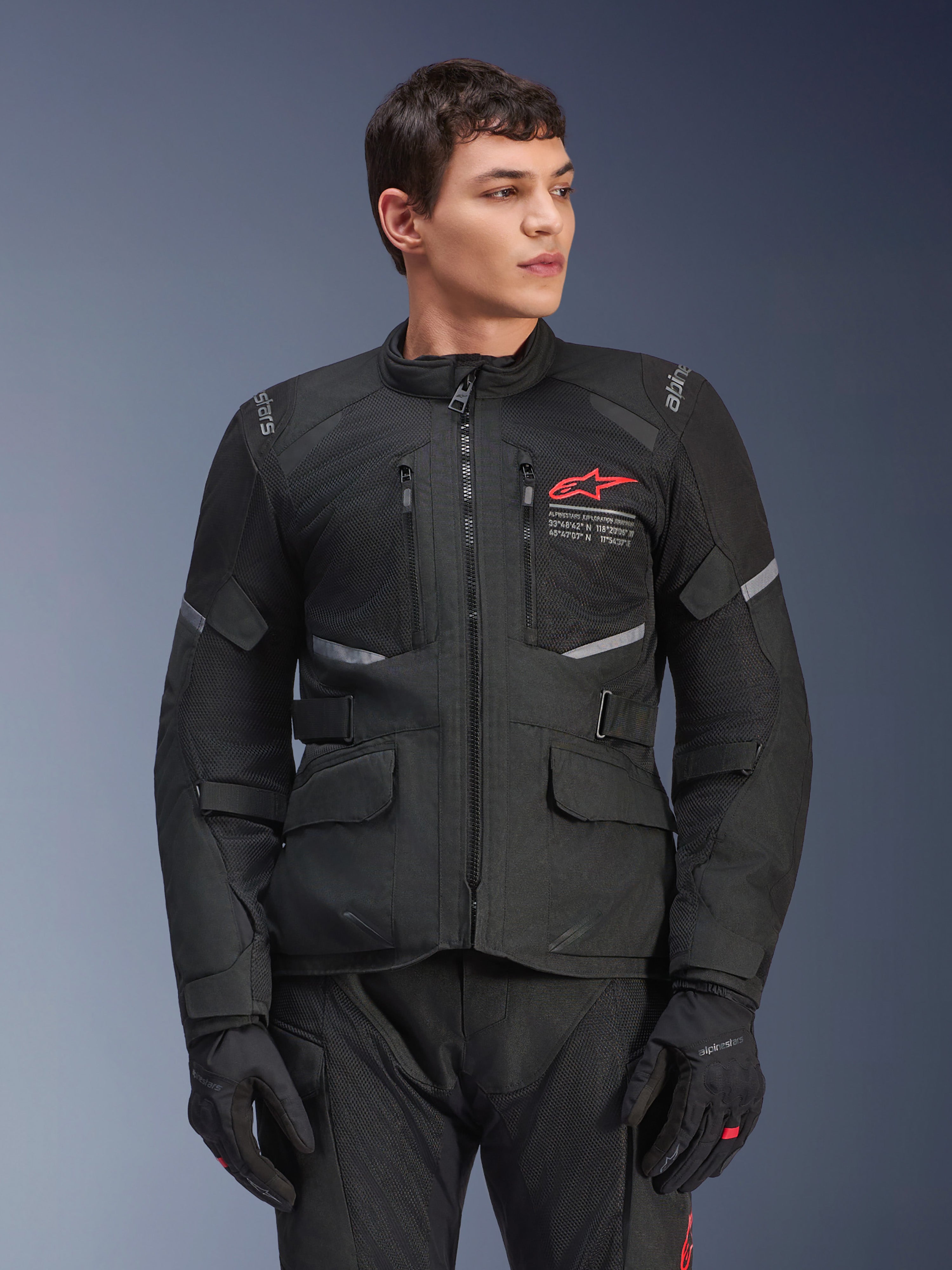 Alpinestars Andes Air Drystar® Jacke, schwarze Motorrad-Tourenjacke, rotes Stern-Logo auf der Brust, mit Mesh-Belüftungseinsätzen und reflektierenden Akzenten, getragen von einem männlichen Model mit schwarzen Motorradhandschuhen, Adventure-Ausrüstung für zwei Jahreszeiten