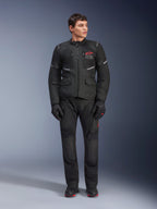 Männliches Model in Alpinestars Andes Air Drystar® Jacke in Schwarz, Adventure-Touren-Motorradausrüstung mit passender Hose und Handschuhen, rotes Logo auf der Brust, Mesh-Belüftung und funktionelle Taschen.
