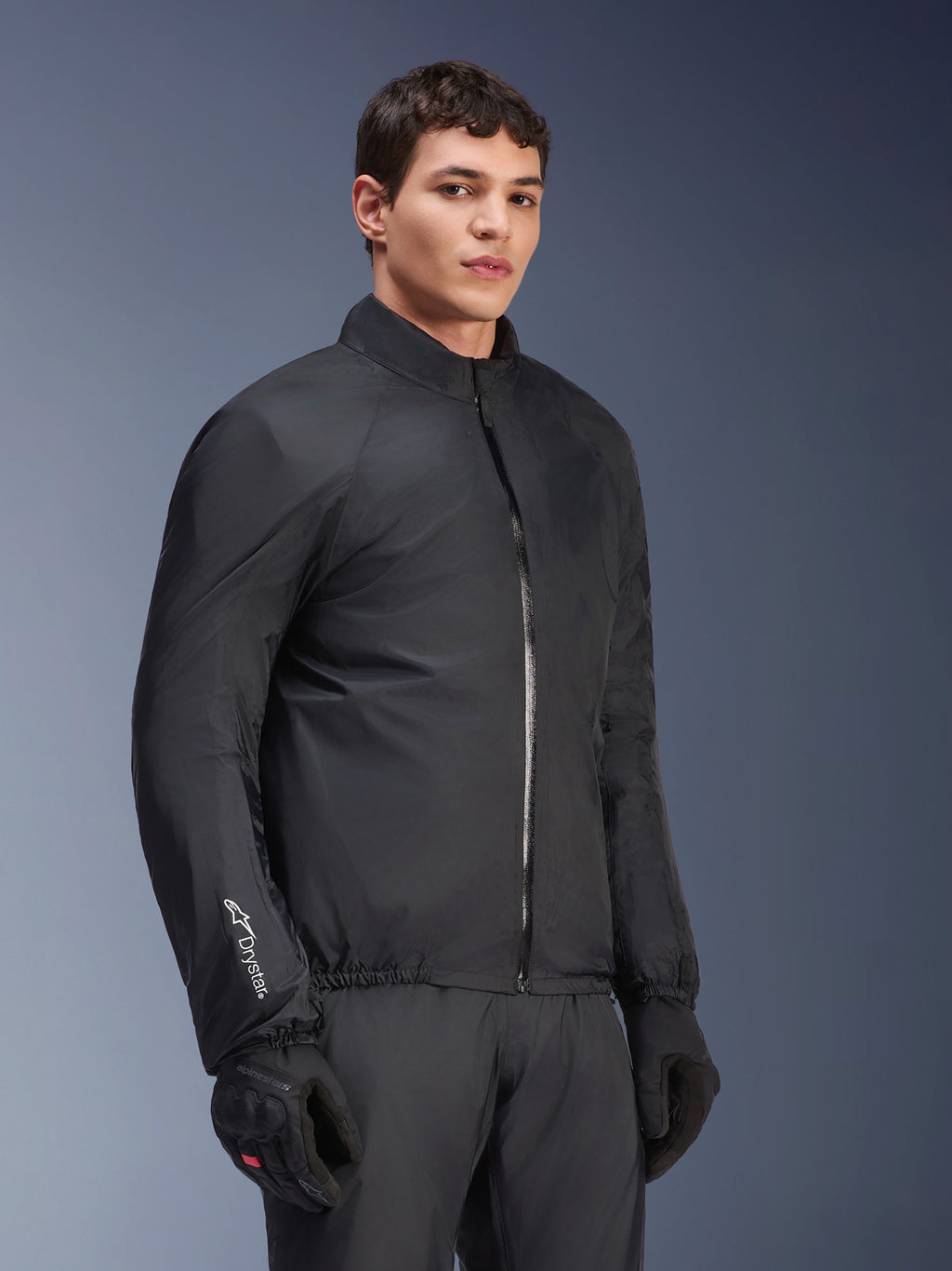 Alpinestars Andes Air Drystar® Jacke, wasserdichte Membran, Schwarz, getragen von einem männlichen Model mit schwarzen Handschuhen und Hose, leichtes technisches Textil mit „Drystar“-Branding am Ärmel, Studioaufnahme