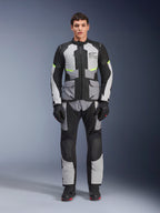 Alpinestars Andes Air Drystar® Jacket in Ice Gray, Dark Gray, and Black, worn by a male model with matching riding pants and gloves, adventure touring design featuring large front pockets and fluorescent yellow accents, studio front view