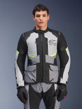 Male rider wearing Alpinestars Andes Air Drystar® Jacket in Ice Gray, Dark Gray, and Black, featuring neon yellow accents and mesh ventilation panels, styled with matching motorcycle pants and gloves, adventure touring gear
