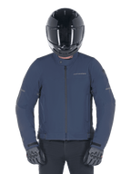Alpinestars Husker Waterproof Jacke, Night Navy, urbane Motorradjacke getragen mit einem schwarzen Integralhelm und grauen Handschuhen, mit technischer Softshell-Außenseite und dezentem Branding