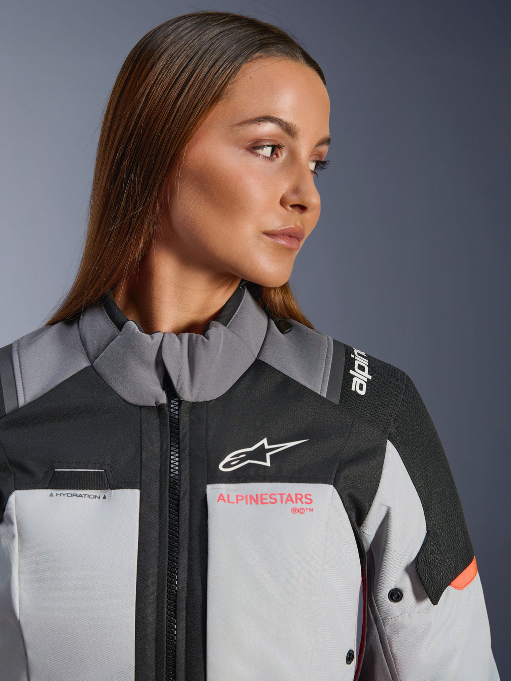 Alpinestars Stella Andes V4 Drystar Damen-Motorradjacke in Grau und Coral Fluo, wasserdichte Adventure-Tourenjacke aus Textil, getragen von einem Model.