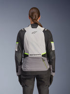 Alpinestars Stella Andes V4 Drystar® Jacke, Abenteuer-Motorradjacke für Damen, Rückansicht, Eisgrau, Dunkelgrau und Schwarz mit gelben Fluo-Akzenten, Alpinestars-Branding auf dem oberen und unteren Rücken, strapazierfähige Textilkonstruktion für Allwetter-Touren