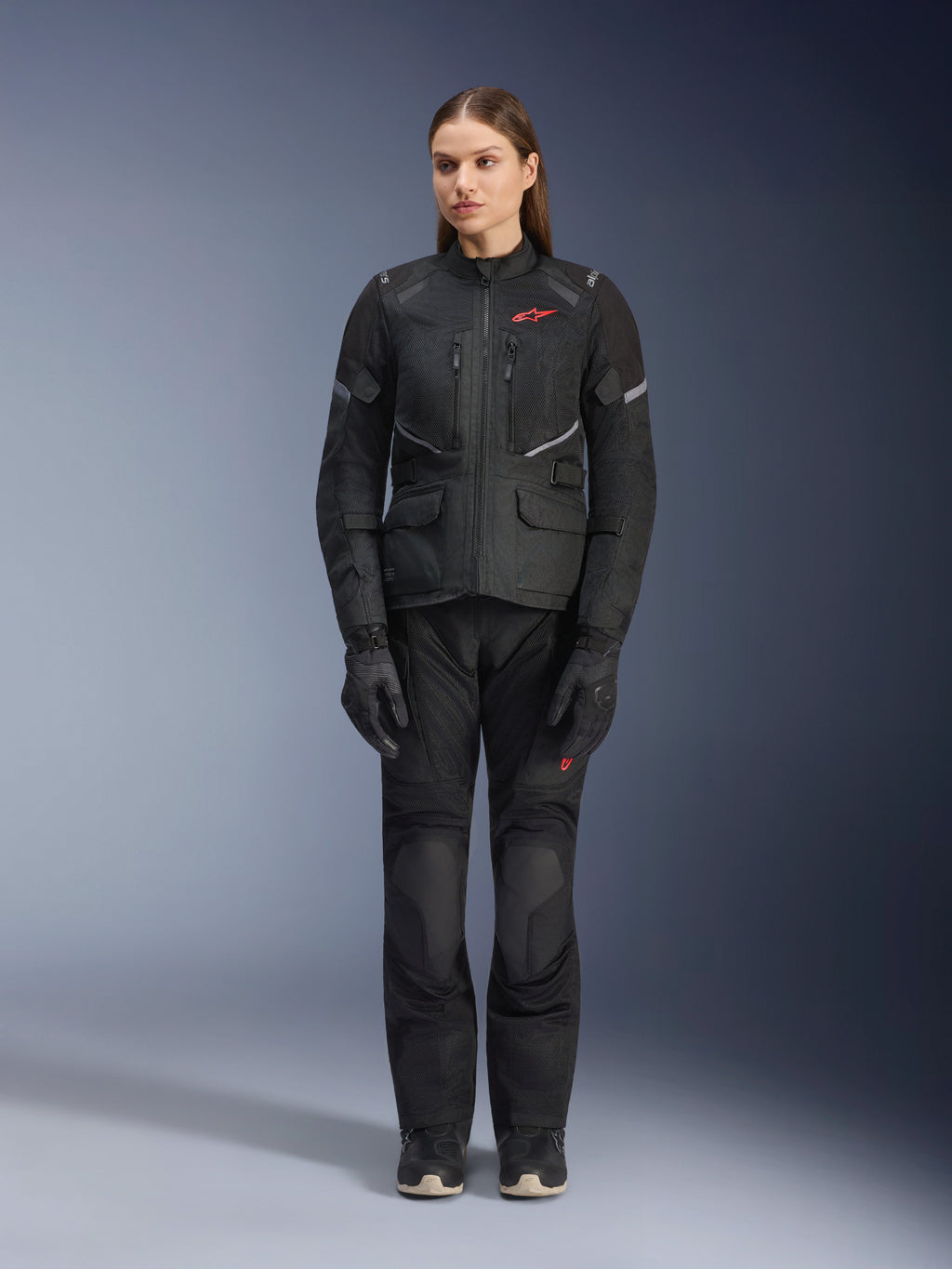 Alpinestars Stella Andes Air Drystar® Jacke in Schwarz, getragen von einem weiblichen Model, kombiniert mit passender schwarzer Tourenhose und Handschuhen, große Mesh-Belüftungseinsätze, rote Logo-Akzente und reflektierende Details, professionelle Studioaufnahme für Damen-Motorradbekleidung.