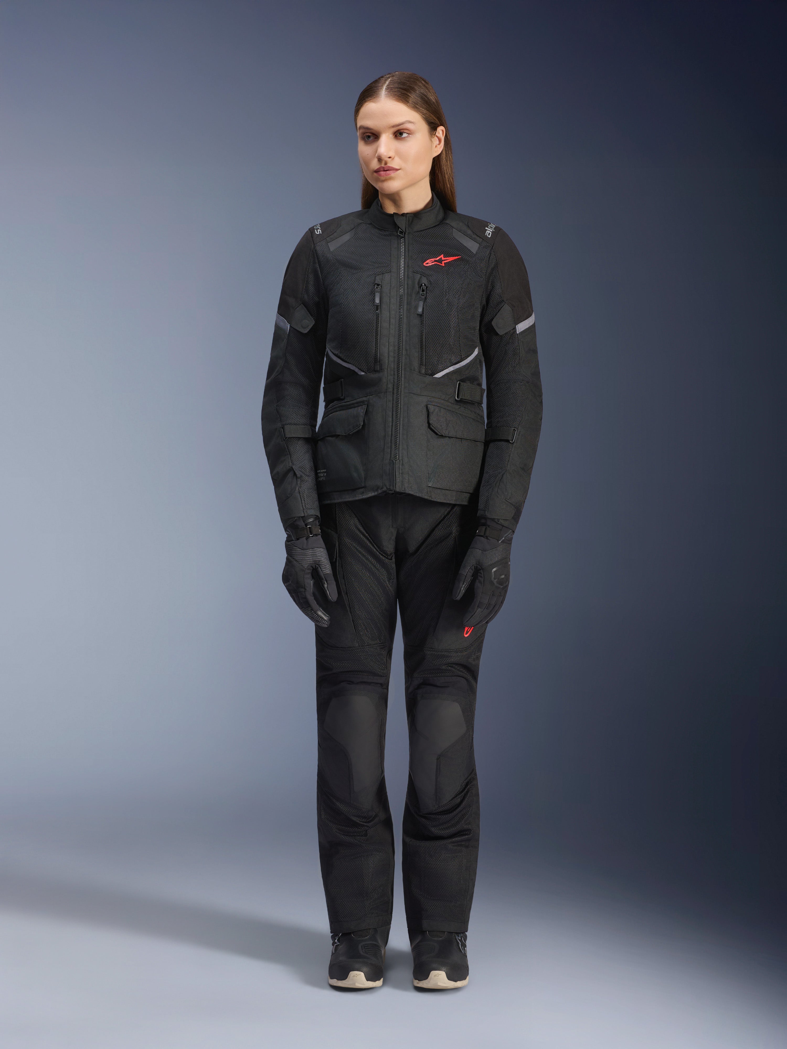 Alpinestars Stella Andes Air Drystar® Jacke in Schwarz, getragen von einem weiblichen Model, kombiniert mit passender schwarzer Tourenhose und Handschuhen, große Mesh-Belüftungseinsätze, rote Logo-Akzente und reflektierende Details, professionelle Studioaufnahme für Damen-Motorradbekleidung.