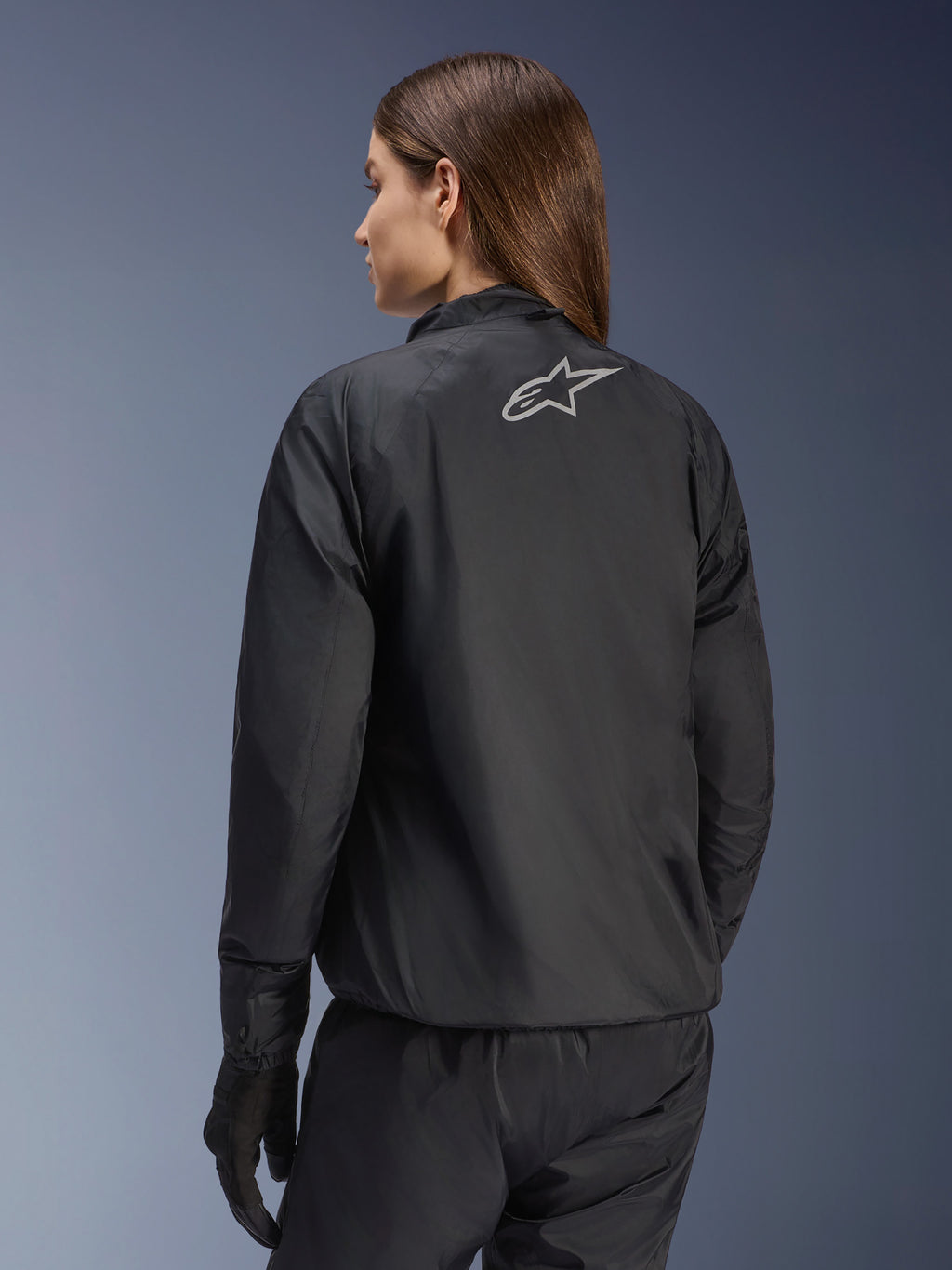 Alpinestars Stella Andes Air Drystar® Jacke, Damen-Motorradjacke, Schwarz, Rückansicht mit silbernem Stern-Logo, kombiniert mit schwarzer Hose und Handschuhen, leichte wasserdichte Tourenbekleidung