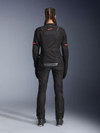 Alpinestars Stella ST-2 Air Jacke, Motorradjacke für Damen, Schwarz, Rückansicht mit rotem Logo auf dem oberen Rücken und grauem Branding am unteren Rücken, getragen mit passender schwarzer Motorradhose und Stiefeln, modernes Touring-Design mit Mesh-Einsätzen und reflektierenden Details.