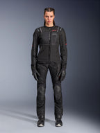 Alpinestars Stella ST-2 Air Jacke, Schwarz, Ganzkörper-Studioansicht einer Fahrerin in passender schwarzer Motorradhose und Handschuhen, mit High-Flow-Mesh-Einsätzen, roten Logo-Details und modernem Touring-Design