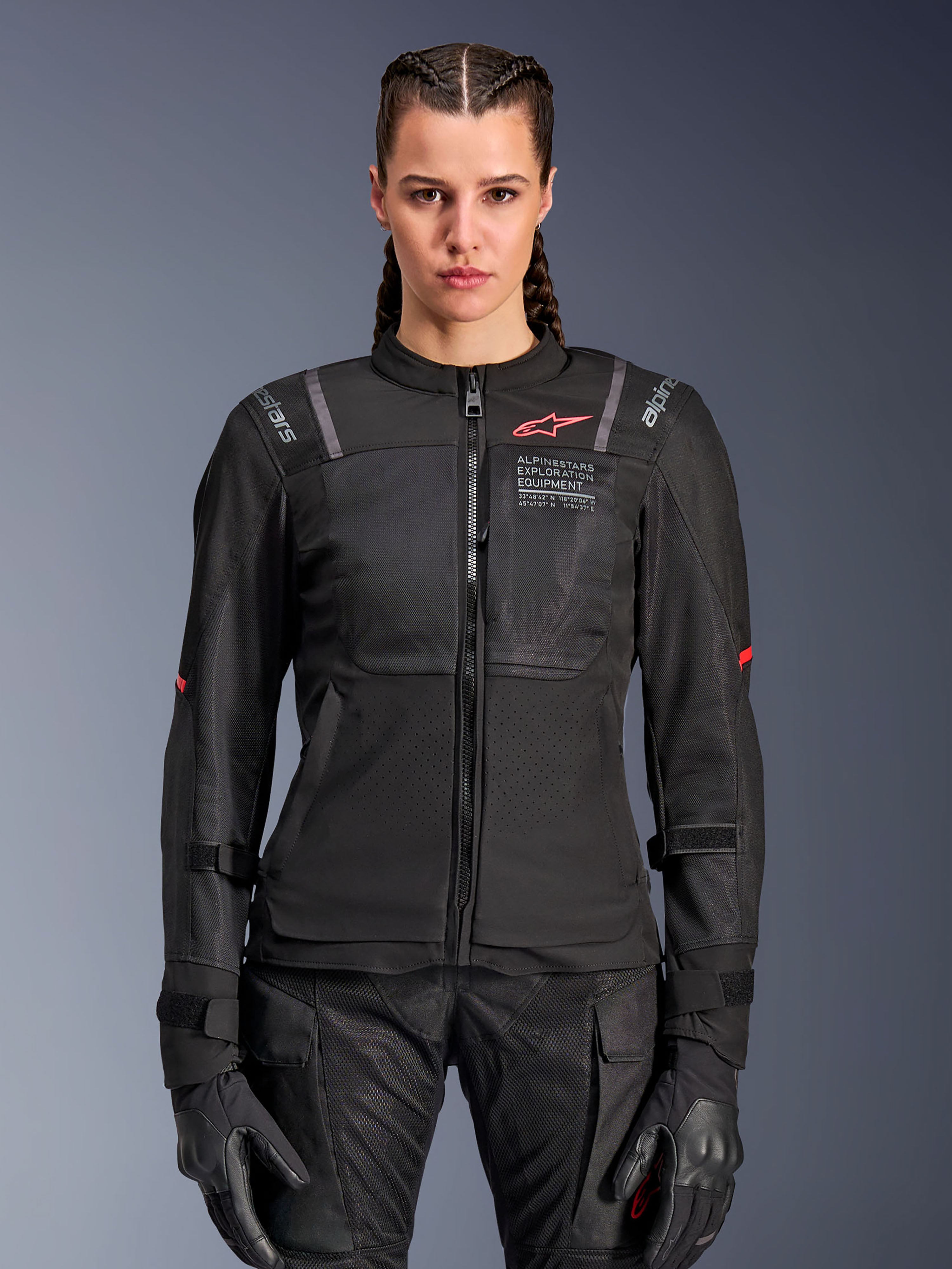 Alpinestars Stella ST-2 Air Damenjacke, Motorradjacke für Damen, Schwarz, Vorderansicht am Modell, mit Mesh-Einsätzen, rotem Logo auf der Brust und Alpinestars Exploration Equipment Branding, getragen mit schwarzen Handschuhen und Motorradhose