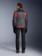Rear view of a model wearing the Alpinestars Woman Stella St-2 Air Jacket in Deep Gray and Dark Gray with Fluo Coral accents, featuring large mesh ventilation panels on the back and reflective logo details, paired with black motorcycle pants and gloves.