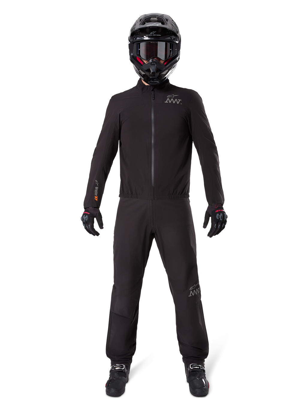 Motorradfahrer in Alpinestars AMT-8 Stretch Drystar® XF Hosenfutter und passender Jacke, komplett schwarze wasser- und winddichte technische Ausrüstung, schwarzer Helm, Handschuhe und Stiefel, schlankes Adventure-Touring-Design.