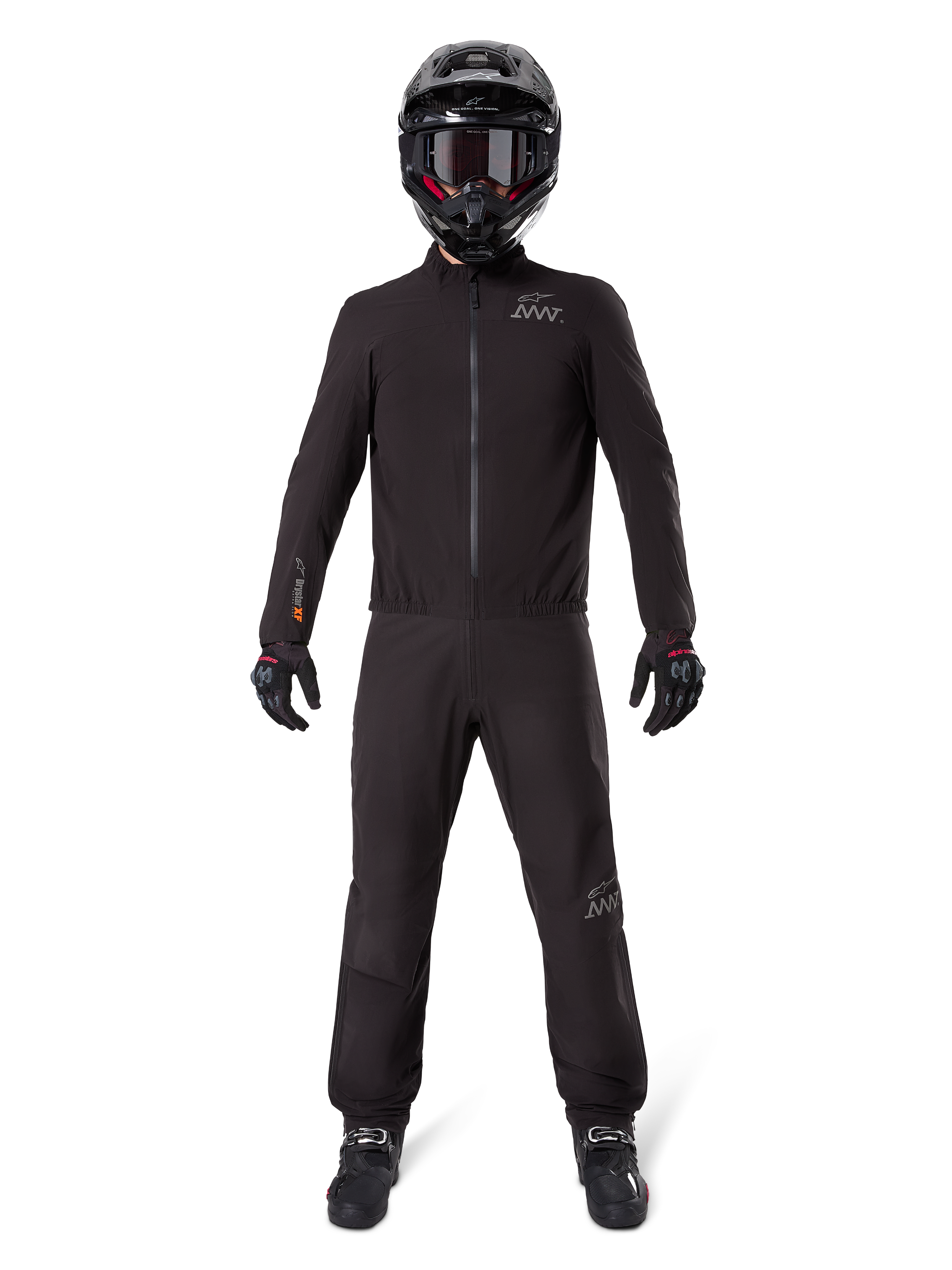 Motorradfahrer in Alpinestars AMT-8 Stretch Drystar® XF Hosenfutter und passender Jacke, komplett schwarze wasser- und winddichte technische Ausrüstung, schwarzer Helm, Handschuhe und Stiefel, schlankes Adventure-Touring-Design.