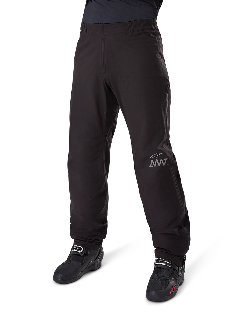 Alpinestars Amt 8 Stretch Drystar® XF Pant Liner, wasserdichte Motorradhose, Schwarz, mit grauem AMT-Logo am unteren linken Bein, getragen mit schwarzen Motorradstiefeln, funktionales Design für Allwetter-Adventure-Fahrten