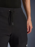 Alpinestars Aeroshell Hose, schwarze Softshell-Motorradhose, Nahaufnahme des elastischen Bunds und Kordelzugverschlusses, modernes minimalistisches Design, strapazierfähige Textilkonstruktion für Freizeit-Touring