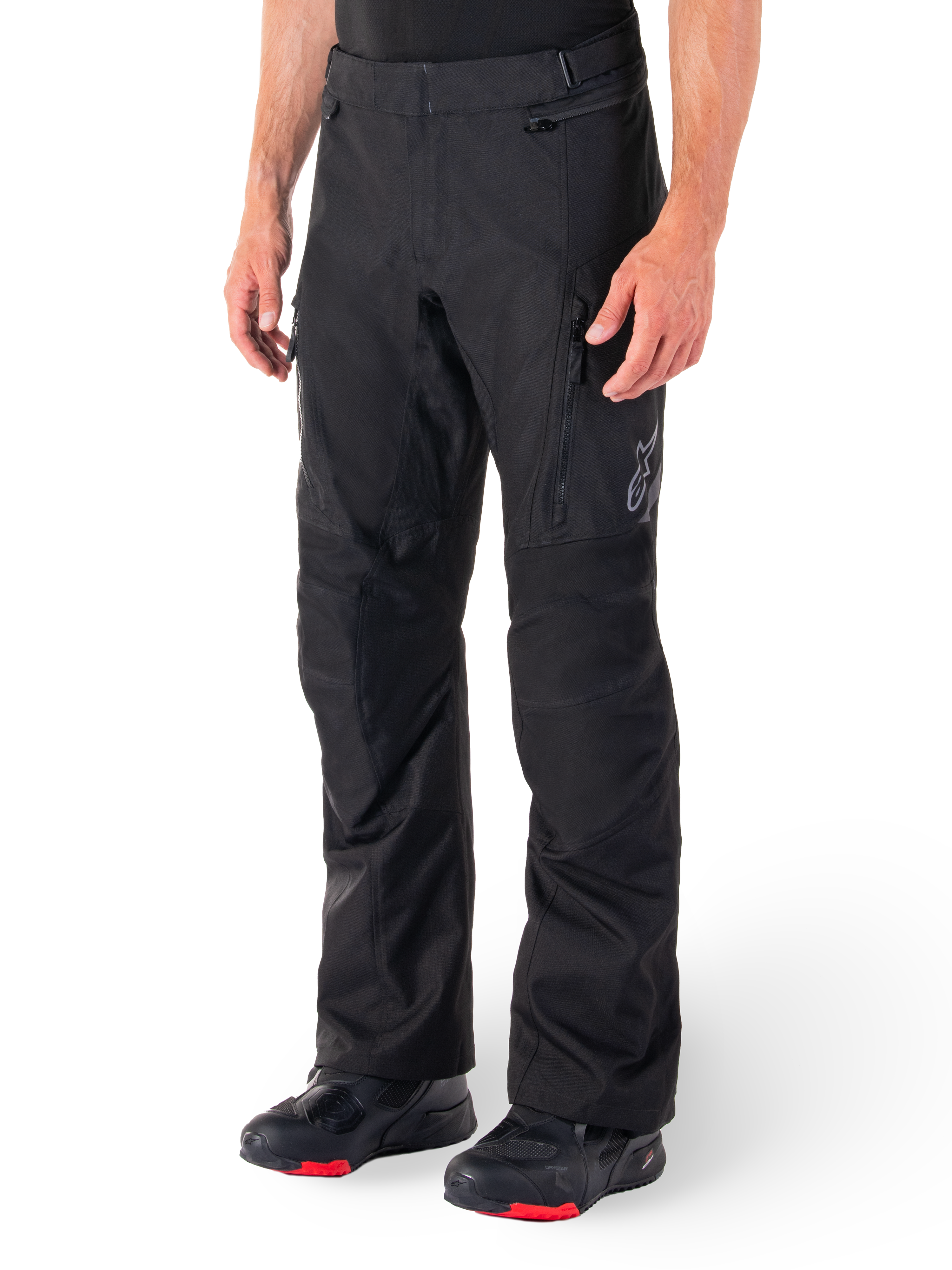 Alpinestars ST-1 Waterproof Pants, Black Motorcycle Touring Pants, worn with black and red riding boots, featuring zippered front pockets and a subtle star logo on the thigh, ergonomic design for adventure and road riding.