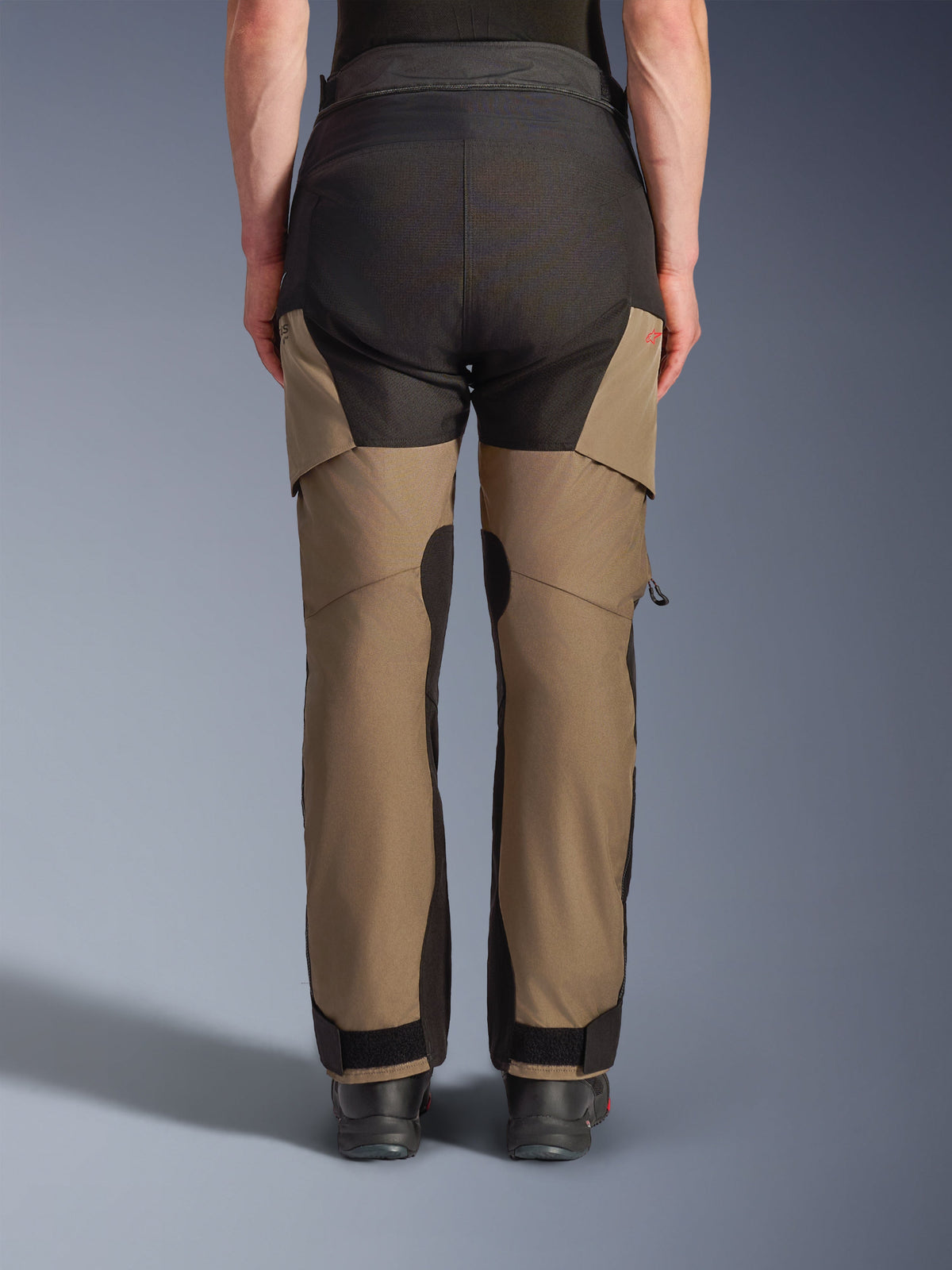 Alpinestars Andes V4 Drystar® Hose, Motorrad-Adventure-Tourenhose, Walnuss und Schwarz, Rückansicht mit verstärkten schwarzen Gesäßpaneelen, rotem Logo-Detail und verstellbaren Knöchelverschlüssen.