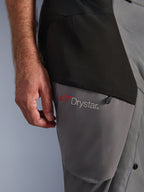 Alpinestars Andes V4 Drystar® Hose, Schwarz Dunkelgrau, Nahaufnahme des Oberschenkel-Details mit rotem Stern-Logo und Drystar®-Branding, strapazierfähige Textilkonstruktion mit Reißverschlusstasche, Adventure-Fahrbekleidung
