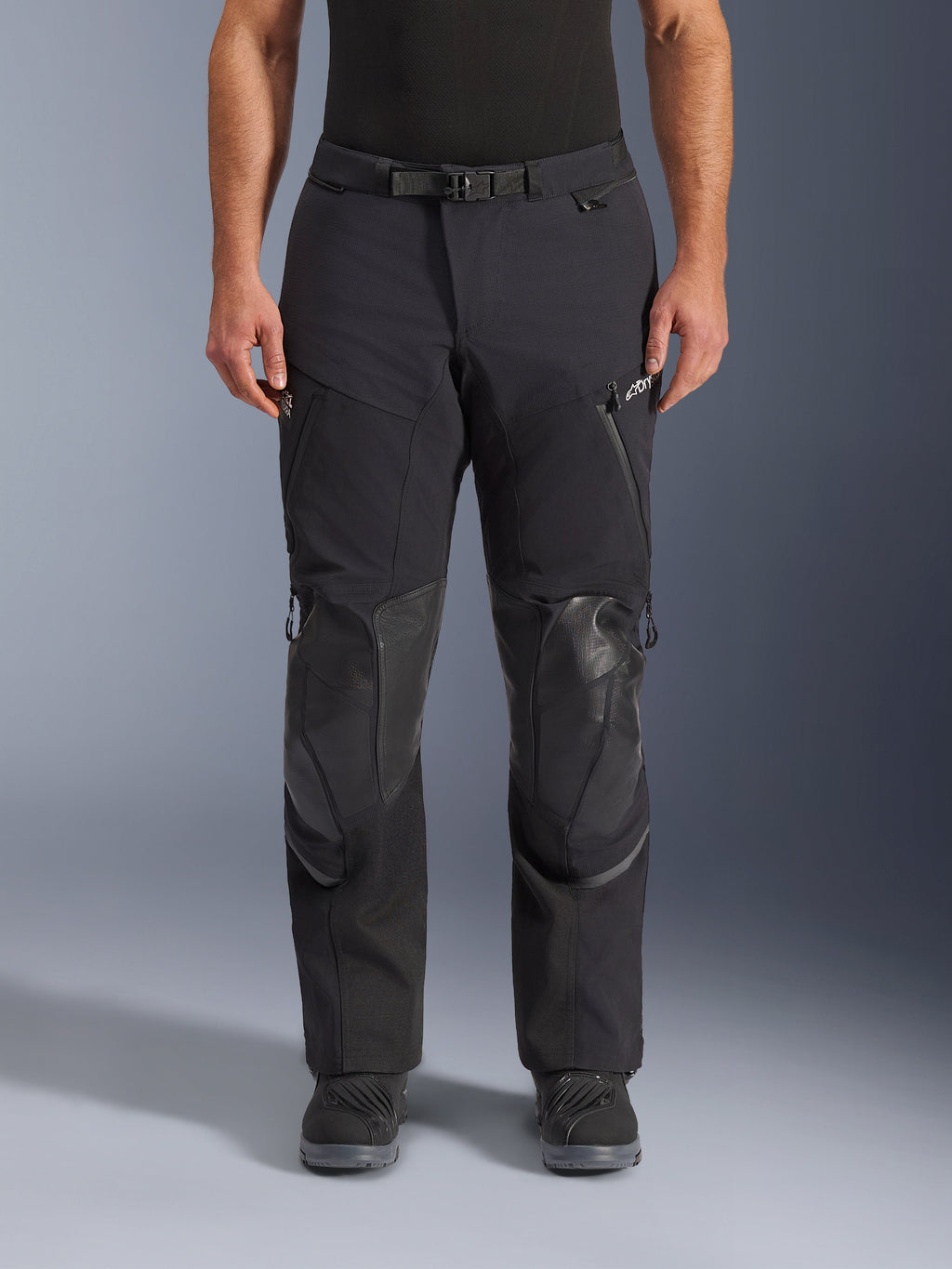 Alpinestars Andes Pro Drystar® XF Hose, Adventure-Touring-Motorradhose in Black Dark Gray, Frontansicht, mit 3-lagiger Laminatkonstruktion, integrierten Knieprotektoren, wasserdichten Reißverschlusstaschen und magnetischem Bundverschluss, kombiniert mit schwarzen Motorradstiefeln.