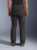 Alpinestars Cusco Drystar® Hose, Motorradhose, Schwarz, Rückansicht getragen von einem Fahrer, mit strukturierten Textilpaneelen, Belüftungsöffnungen mit Reißverschluss an den Oberschenkeln und verstellbaren Knöchelverschlüssen, kombiniert mit schwarzen Alpinestars-Stiefeln.