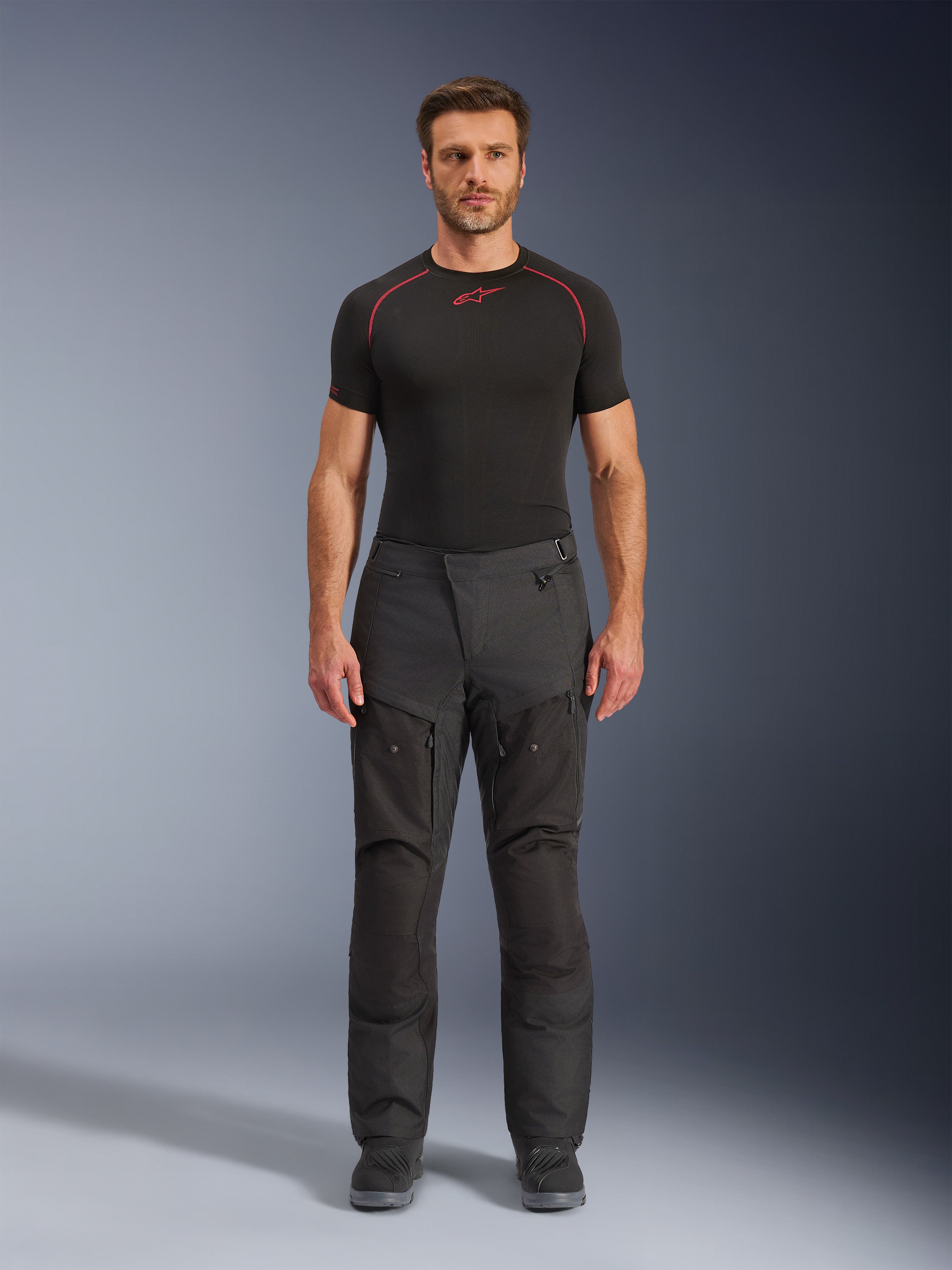 Alpinestars Cusco Drystar® Hose, Motorrad-Adventure-Hose, Schwarz, Ganzkörperansicht von vorne an einem männlichen Model, mit Belüftungsreißverschlüssen an den Oberschenkeln und verstärkten Textilpaneelen, kombiniert mit schwarzem Alpinestars Base Layer