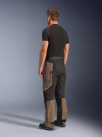 Alpinestars Cusco Drystar® Hose, Adventure-Motorradhose, Walnut Black, Rückansicht in Dreiviertel-Perspektive getragen mit schwarzem Baselayer und Stiefeln, verstärkte Textileinsätze, Cargotaschen mit Reißverschluss an den Oberschenkeln, ergonomische Touring-Passform.