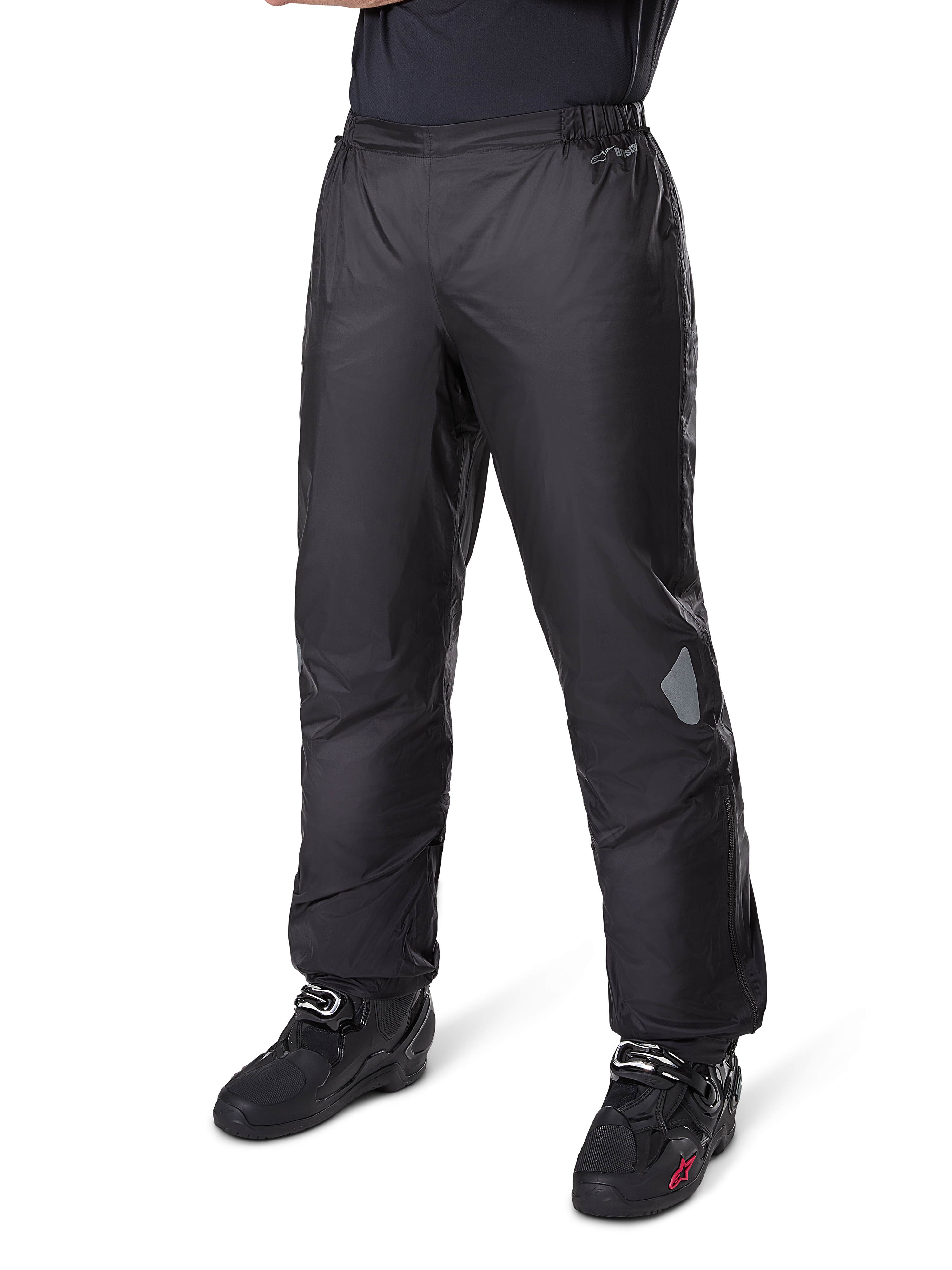 Alpinestars Bogotá Pro Drystar® 3-Jahreszeiten-Hose, Adventure-Touring-Motorradhose, Schwarz, getragen mit schwarzen Motorradstiefeln, mit reflektierenden Einsätzen an den Knien und Drystar-Logo, leichtes wasserdichtes Textildesign für das Fahren zu jeder Jahreszeit.