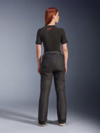 Rückansicht eines Models in der Alpinestars Stella Andes V4 Drystar® Hose in Schwarz, kombiniert mit einem schwarzen, kurzärmeligen Baselayer mit rotem Alpinestars-Logo, Adventure-Touring-Motorradausrüstung mit strapazierfähiger Textilkonstruktion.