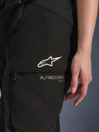 Alpinestars Stella Andes V4 Drystar® Hose, Damen-Motorradhose, Schwarz, Nahaufnahme der Cargo-Tasche am Oberschenkel mit weißem Stern-Logo und Branding, strapazierfähiges Textilmaterial für Adventure-Touring